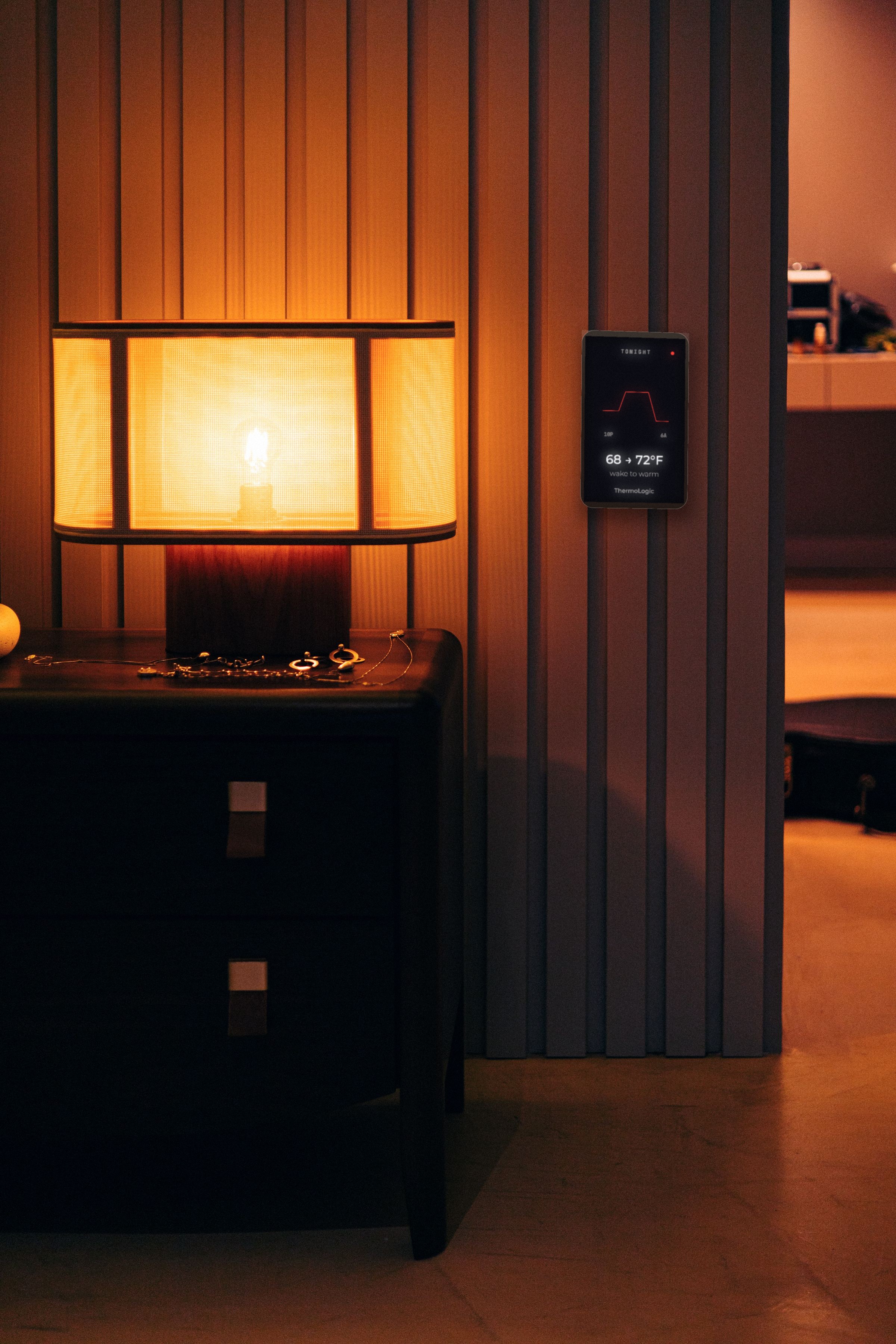 Warm lamp on a dark nightstand against slat wall
