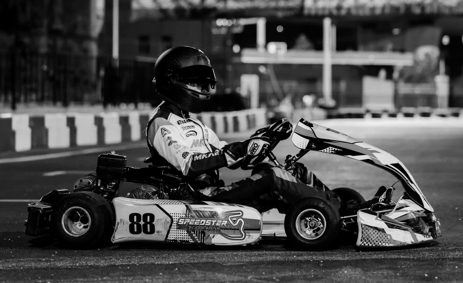 Racing kart on track under floodlights at night, black and white