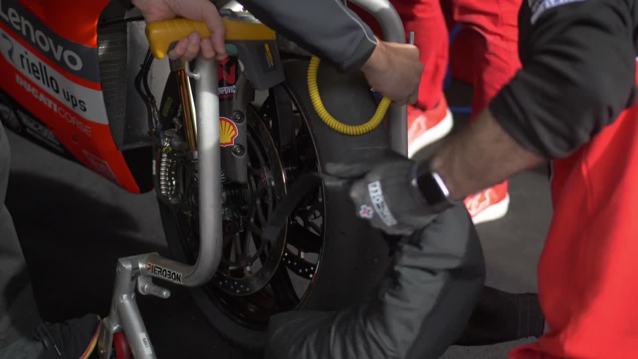 A plain black tire warmer being fitted to a racebike's front wheel